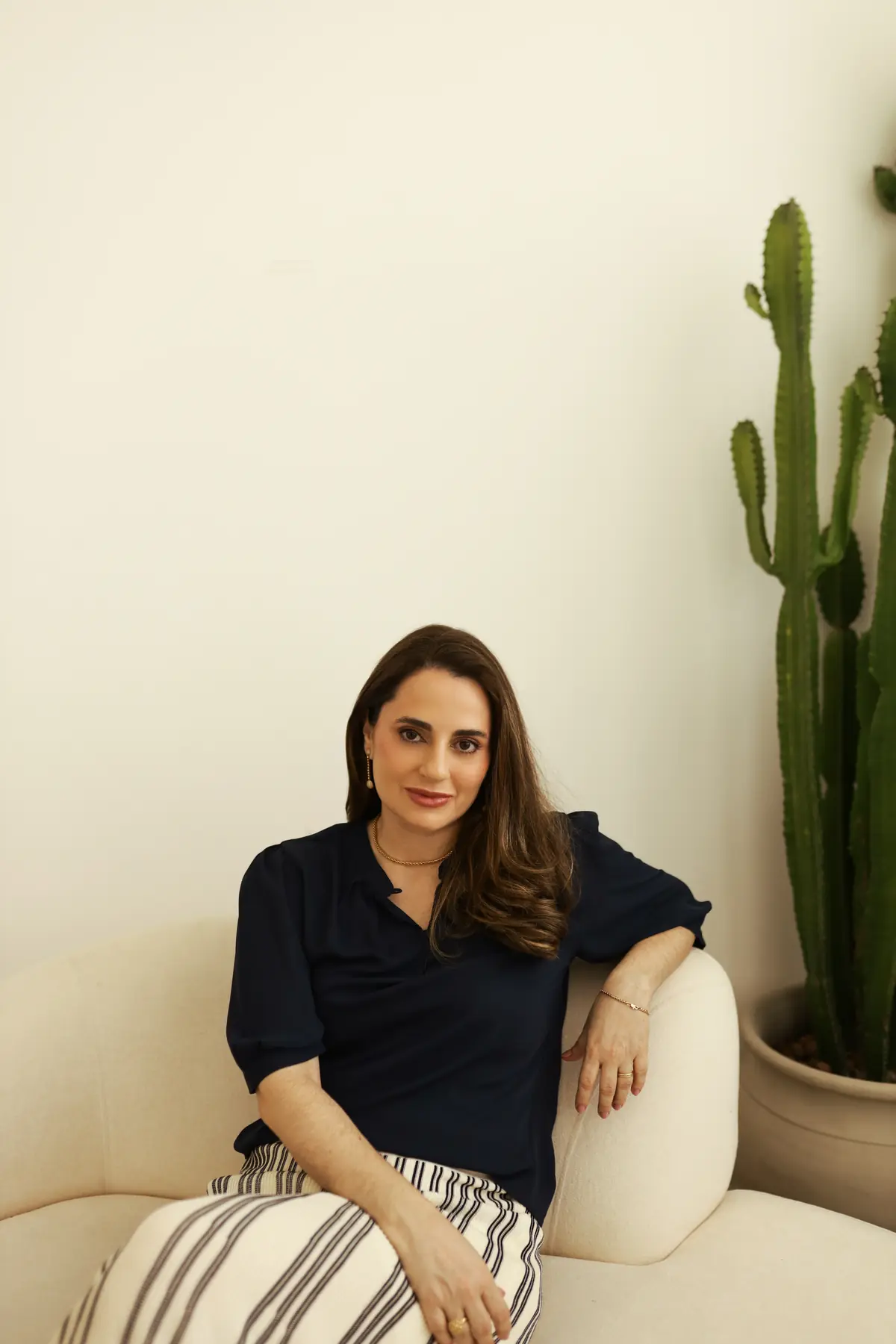Dra. Viviane Curi sorrindo no sofá do consultório